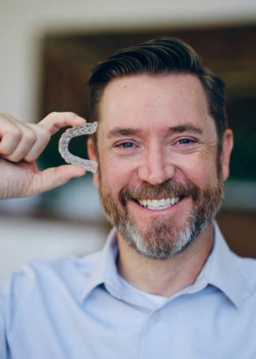 A man holding invisible dental teeth aligners.